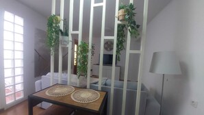 A room with a dining table, a grey sofa, a lamp, and a white partition with plants. - Nice house with terrace (San Cristóbal De La Laguna)