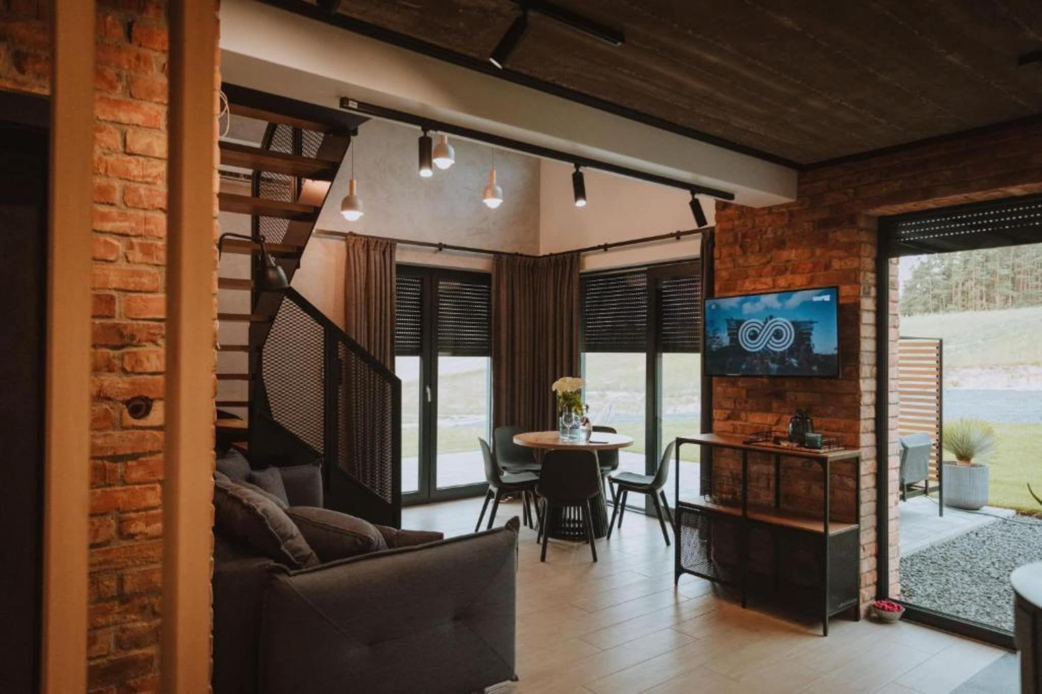 Un salon moderne avec un escalier, un coin repas et un téléviseur.