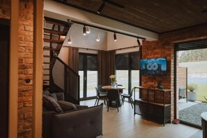 A modern living room with a staircase, a dining area, and a television.