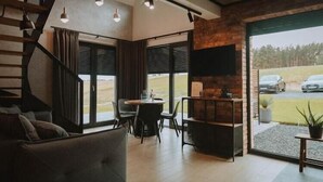 Un interior moderno con una escalera, un comedor y un amplio ventanal que ofrece vistas al exterior.