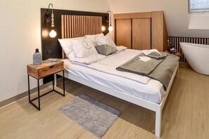 A modern bedroom with a bed, bedside tables, a nightstand, a floor lamp, a bedside table lamp, a rug, and a bathtub. - Holiday home, bedroom with bathtub, jacuzzi (Kościerzyna)