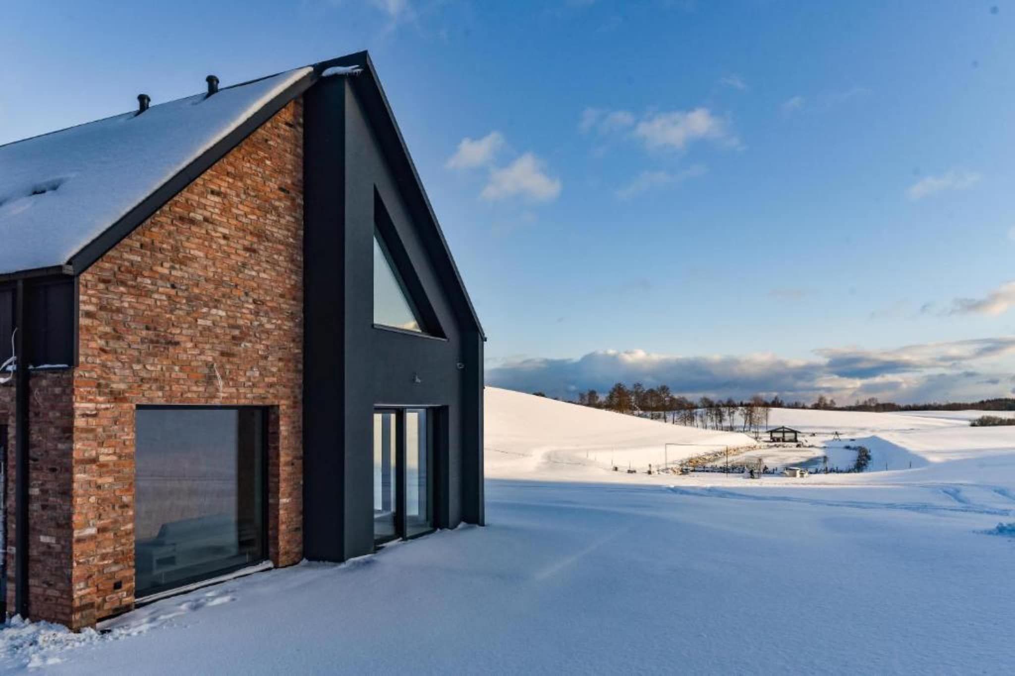A modern building with a brick facade and large windows, set against a snowy landscape.