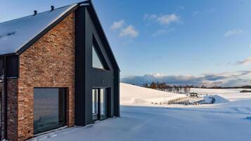 A modern building with a brick facade and large windows, set against a snowy landscape.