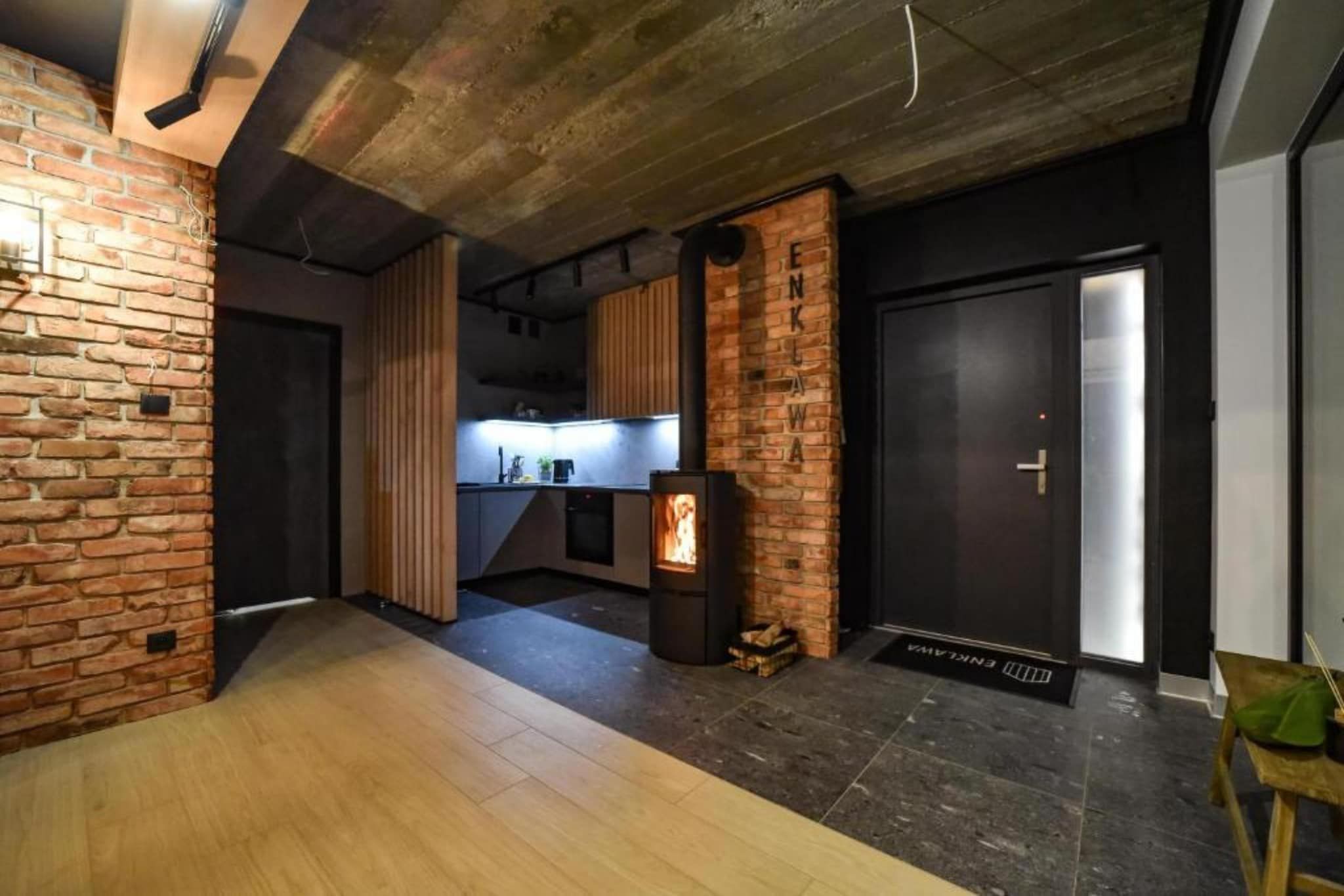 Een modern interieur met zichtbare bakstenen muren, een keukenhoek en een open haard.