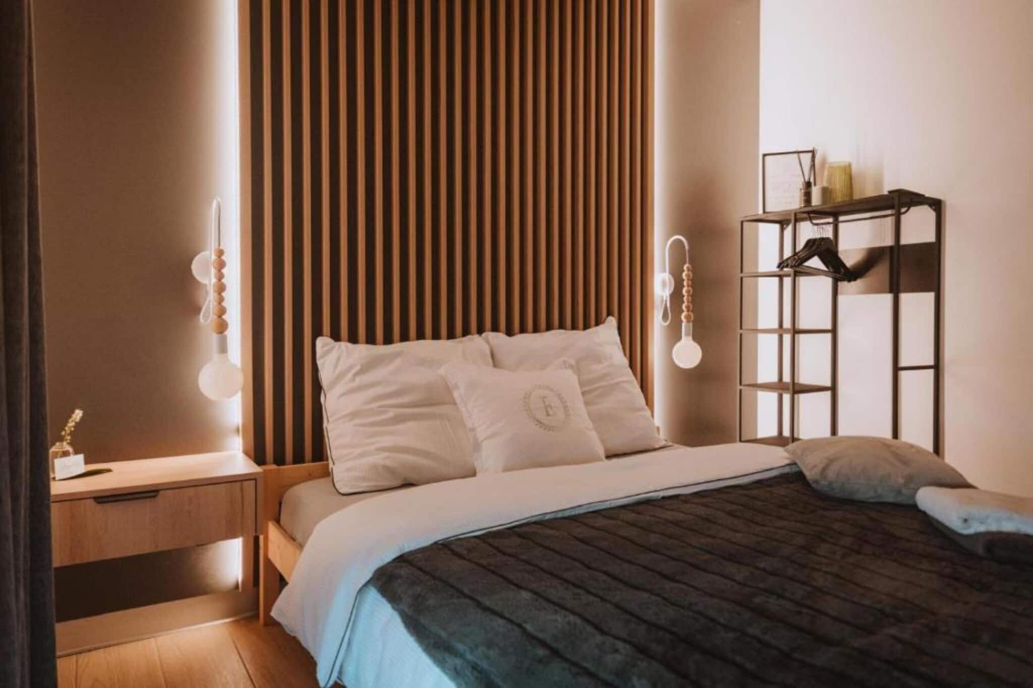 A bedroom with a bed, bedside tables, a wardrobe, and a wall-mounted light fixture.