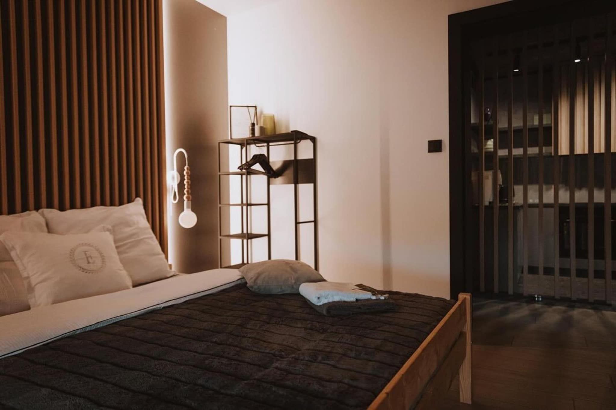 A modern bedroom with a bed, a bedside table, a wall-mounted light, and a wardrobe.