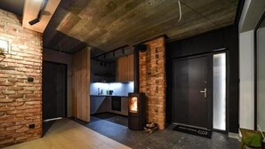 Una cocina moderna con pared de ladrillo, revestimiento de madera, una puerta negra y una chimenea.