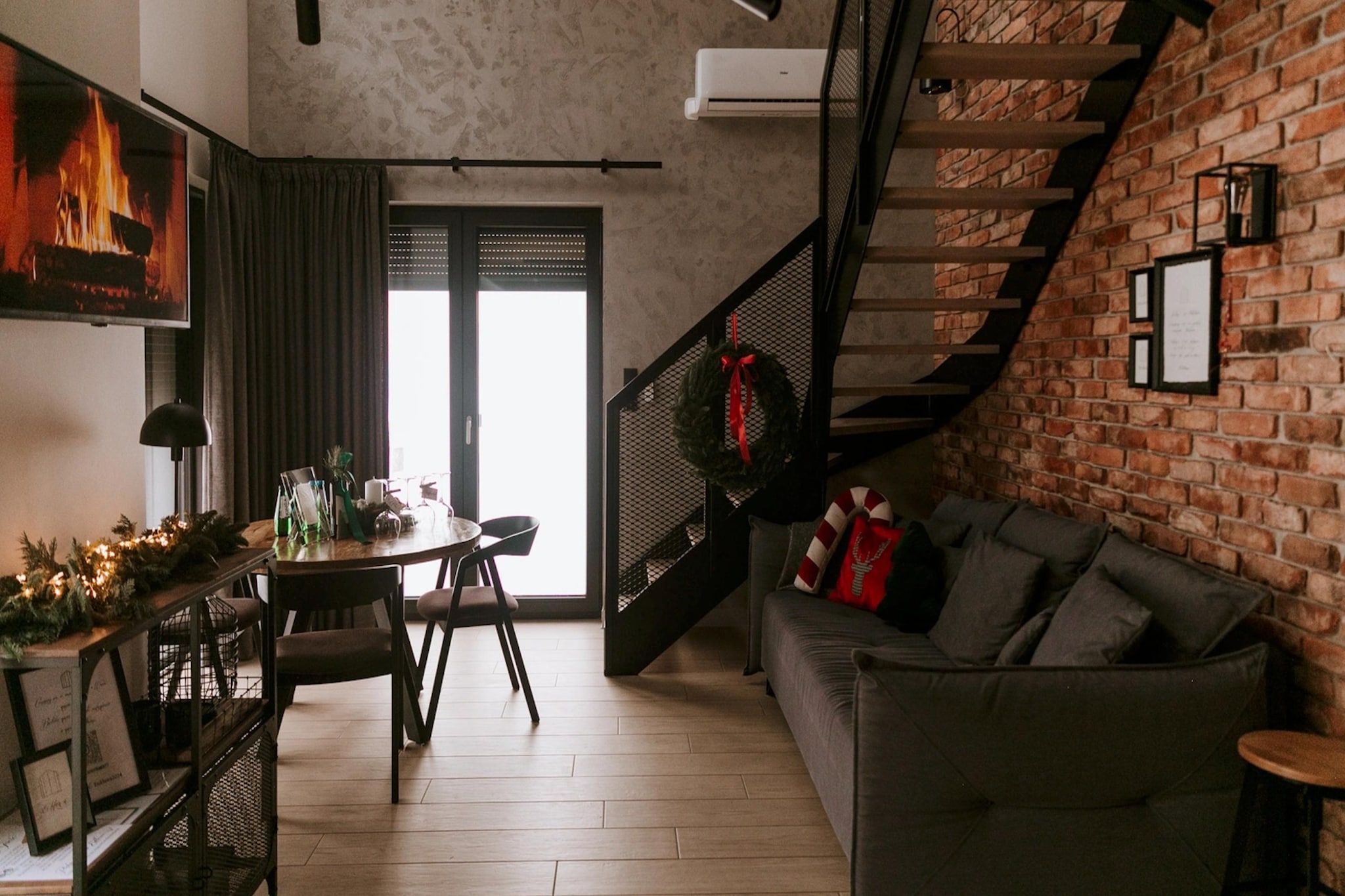 A modern living room with a fireplace, a dining area, and a staircase leading to an upper level.