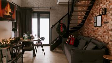 A modern living room with a fireplace, a dining area, and a staircase leading to an upper level.