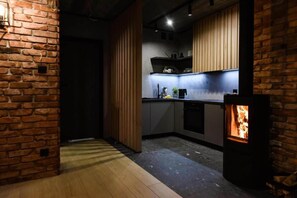 A modern kitchen with a brick wall, wooden cabinets, and a built-in stove. - Holiday home, bedroom with bathtub, jacuzzi (Kościerzyna)
