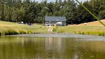 Una propiedad junto al lago con un edificio, zonas verdes y un estanque.