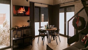 Una sala de estar moderna con chimenea, un comedor y una escalera adornada con un adorno navideño.