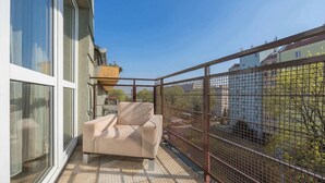 A balcony with a cushioned chair, a potted plant, and a view of neighboring buildings. - Spacious Apartment with Balcony | Parking | Close to Attractions (Warszawa)
