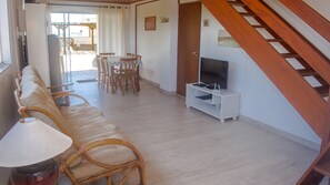 A living room with a sofa, chairs, a TV on a stand, and a staircase. - Mirante dos Ingleses (Florianopolis)