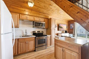Una cocina con armarios de madera, horno de acero inoxidable, microondas y pileta.