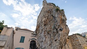 Eine hohe, felsige Klippe mit einem Gebäude am Fuße.