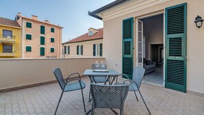 Eine Terrasse mit Tisch und Stühlen, ein Gebäudeeingang und der Blick auf umliegende Häuser.