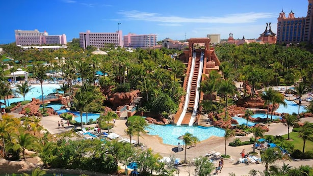 A resort with a water slide, multiple pools, and palm trees. - Harborside Resort at Atlantis-2 Bedrooms and Full Resort Access (N.P)