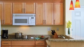 A kitchen with wooden cabinets, a microwave, a coffee maker, a sink, and a vase with flowers. - Harborside Resort at Atlantis-2 Bedrooms and Full Resort Access (N.P)