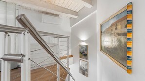 Un escalier avec des rampes en métal, un plancher en bois et un mur orné de tableaux encadrés.