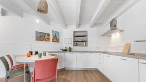 Une cuisine moderne avec des meubles blancs, une table ronde et des chaises colorées.