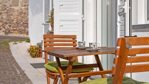 Une table en bois, deux chaises, une paire de tasses et une petite plante en pot.