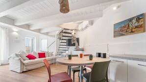 Un salon moderne comprenant un canapé, des fauteuils, une table à manger et un escalier.