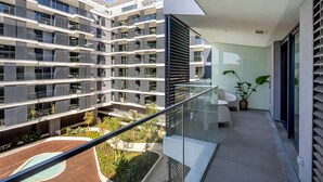 Ein modernes Apartmenthaus mit Balkonen, einem Pool und einer kleinen Gartenanlage.
