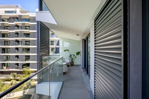 A modern balcony with a glass railing, a potted plant, and a view of adjacent buildings. - Modern Lisbon W Balcony II by Homing (Lisbon)