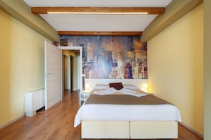 Ein Hotelzimmer mit einem Bett, einer Stadtlandschaft als Wandbild und einer Holzzieldecke.