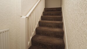 Eine Teppichstufen Treppe mit weißen Wänden und einem weißen Geländer.