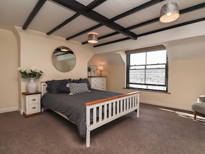 A bedroom with a bed, a nightstand, a dresser, a mirror, and a window with a view. - Marina House (Whitby)