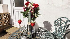 Ein Tisch mit einer Weinflasche, einem Glas und einem Blumenstrauß.
