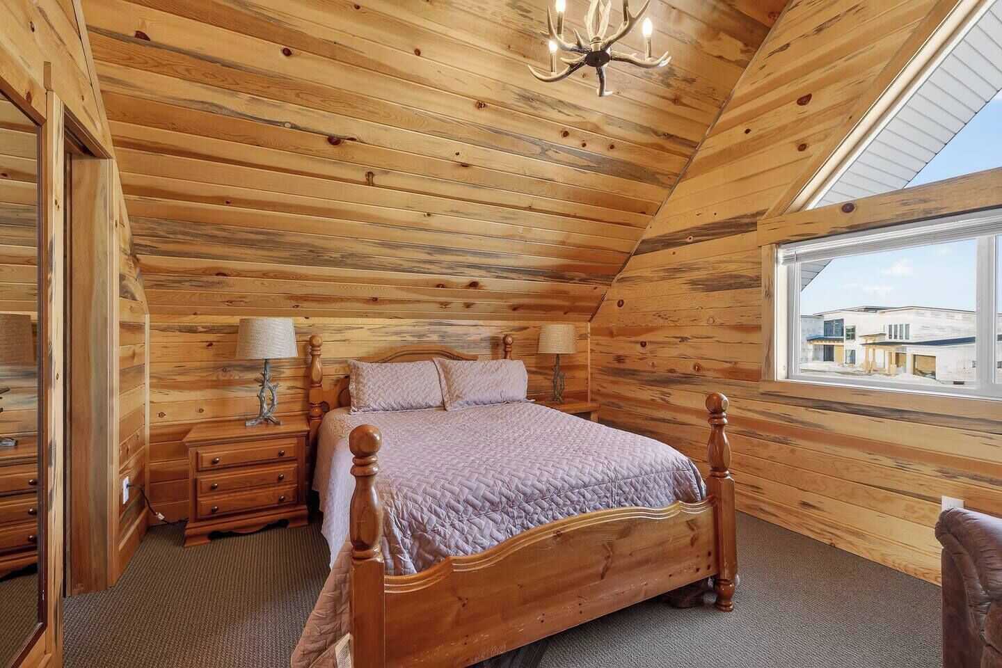 A wooden-paneled bedroom with a bed, nightstands, lamps, and a window.