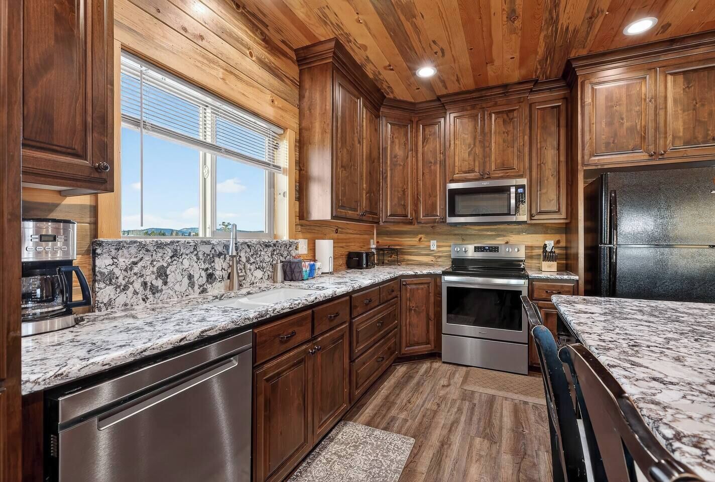 Una cocina con armarios de madera, un refrigerador de acero inoxidable, un microondas y un horno empotrado.