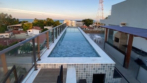 Una piscina infinita en la azotea, con barandilla de cristal, con vistas a la ciudad y al mar.