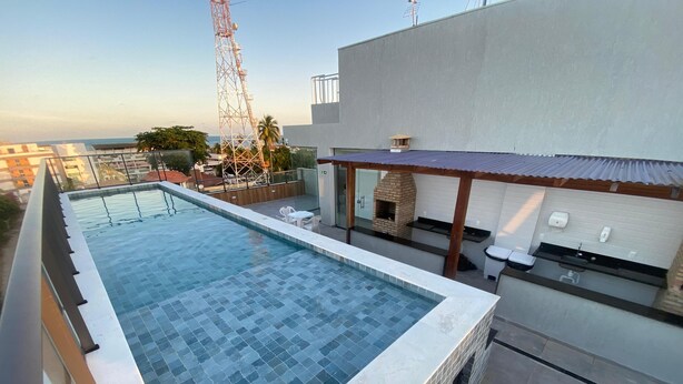 Una piscina en la azotea con vistas al horizonte urbano, un horno de ladrillo y una pequeña cocina al aire libre.