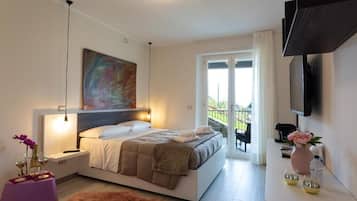 A modern bedroom with a bed, bedside table, artwork, and a balcony view.