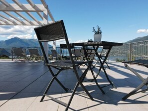 A terrace with a table and chairs, a potted plant, and a view of mountains. - Domus Bellagio (Bellagio)