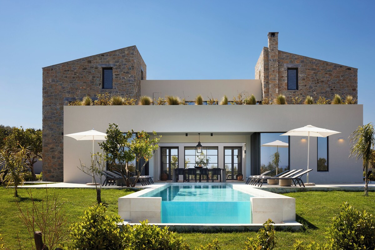A modern house with a pool, stone walls, and outdoor seating.