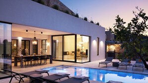 Ein modernes Haus mit Swimmingpool, Sitzgelegenheiten im Freien und Essbereich.