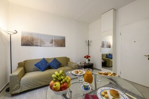 Ein modernes Zimmer mit einer Couch, einem Esstisch mit Frühstück, einem Spiegel und Kunstwerken an der Wand.