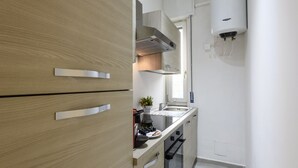 A compact kitchen with wooden cabinets, a built-in oven, and a wall-mounted water heater. - Monte Ceneri, 71 - Modern, convenient and well-connected (Milan)