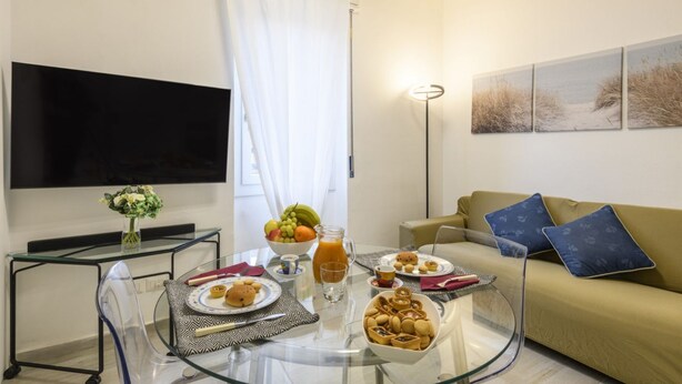 A living room with a glass coffee table, a sofa, a flat-screen TV, and a painting on the wall. - Monte Ceneri, 71 - Modern, convenient and well-connected (Milan)