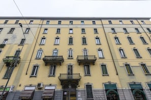 Ein mehrstöckiges Gebäude mit gelber Fassade, zahlreichen Fenstern und Balkonen.