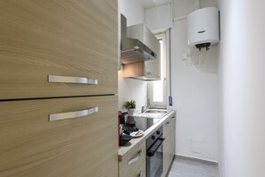 Eine kleine Küche mit Holdekor, einem Einbauofen und einem an der Wand montierten Durchlauferhitzer.