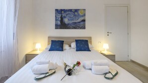 A hotel room with a large bed, two nightstands, a painting above the bed, and a door to the right. - Monte Ceneri, 71 - Modern, convenient and well-connected (Milan)