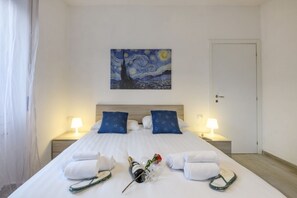 A hotel room with a large bed, two nightstands, a painting above the bed, and a door to the right. - Monte Ceneri, 71 - Modern, convenient and well-connected (Milan)