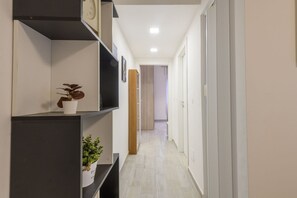 A hallway with a plant on a shelf, a clock, and a door at the end. - Monte Ceneri, 71 - Modern, convenient and well-connected (Milan)