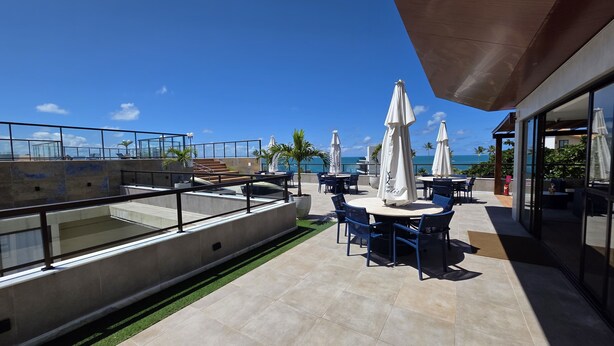 Eine Dachterrasse mit Außenmöbeln, einem Pool und Blick auf den Ozean.